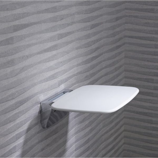 white rectangular shower seat with chrome bracket on a grey wall. the seat is folded in the down position.