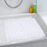 square, plastic shower mat composed of white pebble shapes in situ photo on a plain white, square shower tray in a white bathroom