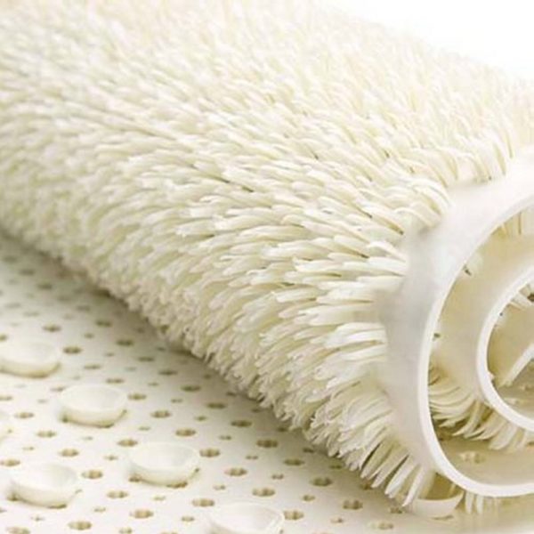 section of a rolled up cream coloured bath mat with soft plastic bristle texture on top and suction cups underneath
