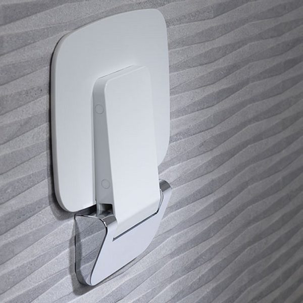 white rectangular shower seat with chrome bracket on a grey wall. the seat is folded in the up position.