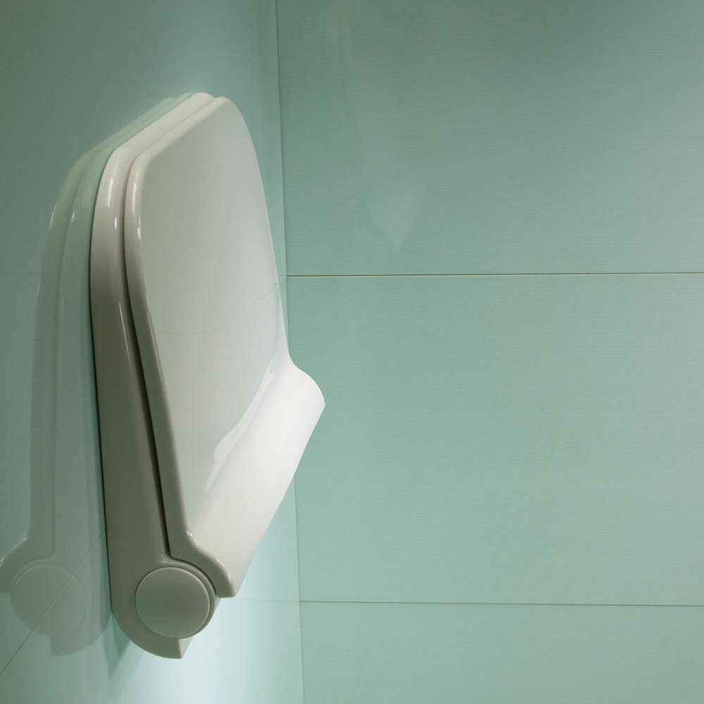 white shower seat mounted on a wall . it is in the folded up position