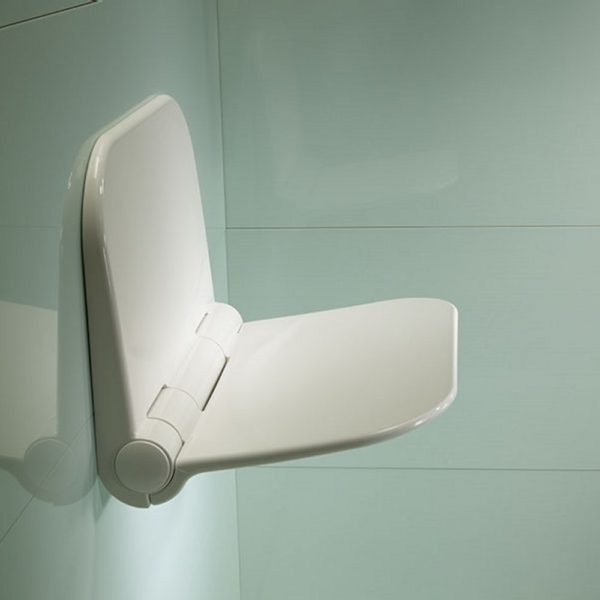 white shower seat mounted on a wall . it is in the folded down position