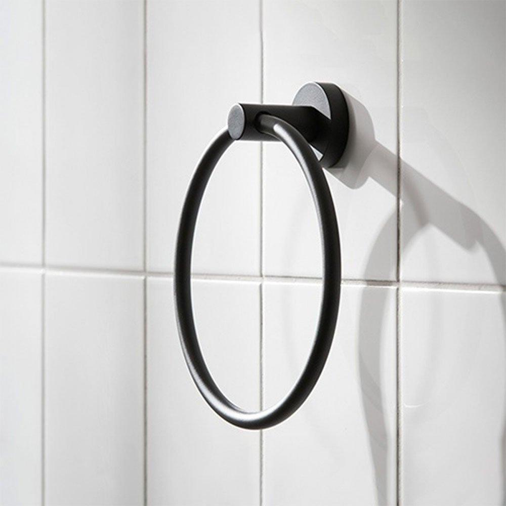 black circular shaped towel ring with circular wall mount on a white tiled wall
