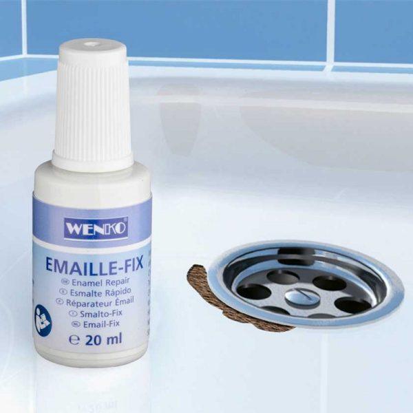 white bottle with blue label next to a chrome drain on a white enamel shower tay, there is a chip in the eamel by the brain showing a brown wood underneath
